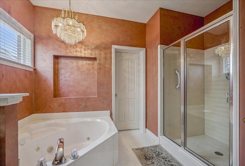 Full bathroom with suspended lighting, a tub with jets, and a shower stall