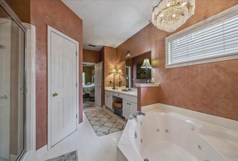 Full bath featuring vanity, ensuite bath, hanging lights, a jetted tub, and a stall shower