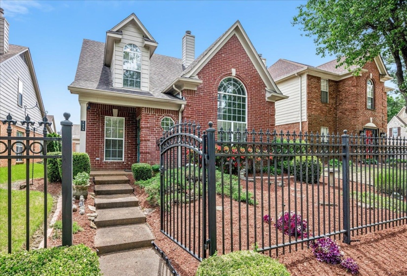 View of front of home with a fenced front yard, brick siding, a gate, a shingled roof, and a chimney