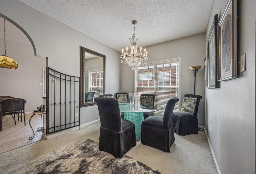 Dining room with light colored carpet, a chandelier, and a textured ceiling