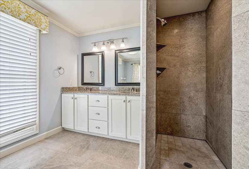 Bathroom with double vanity, tiled shower, and crown molding