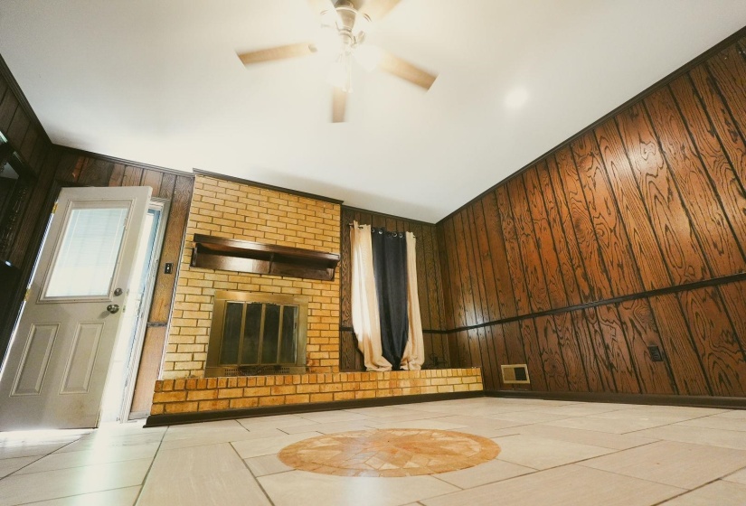 Unfurnished living room featuring wooden walls and a ceiling fan