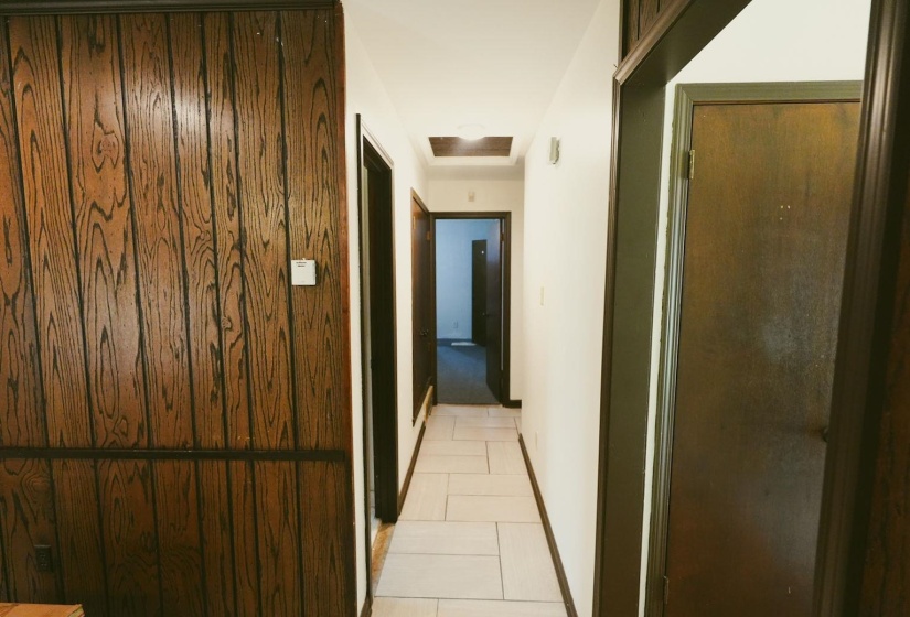 Hallway featuring light tile patterned flooring and attic access