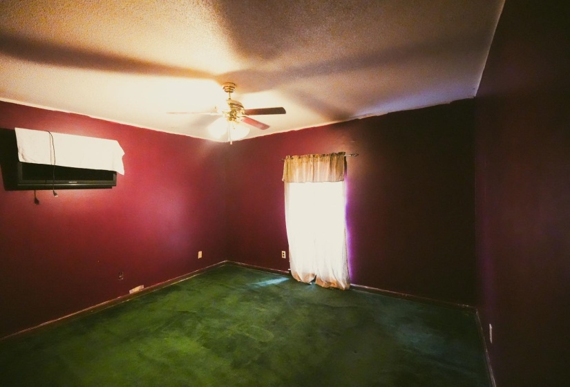 Empty room with dark colored carpet, a textured ceiling, and a ceiling fan