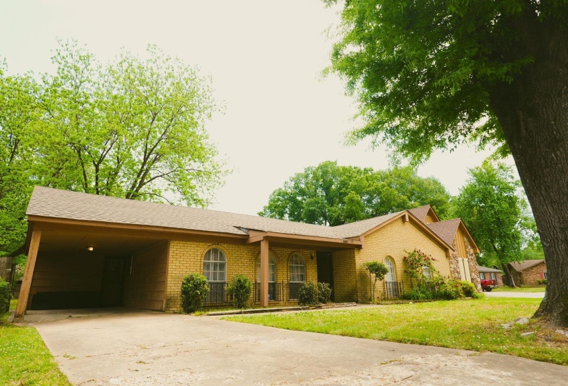 Ranch-style home with a front lawn, concrete driveway, brick siding, and an attached carport