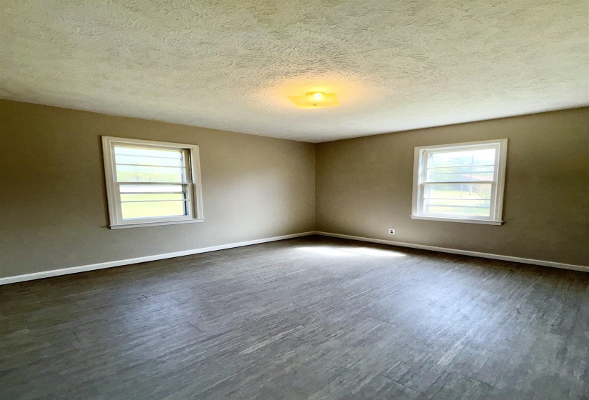 Unfurnished room featuring dark wood-type flooring, a textured ceiling, and healthy amount of natural light