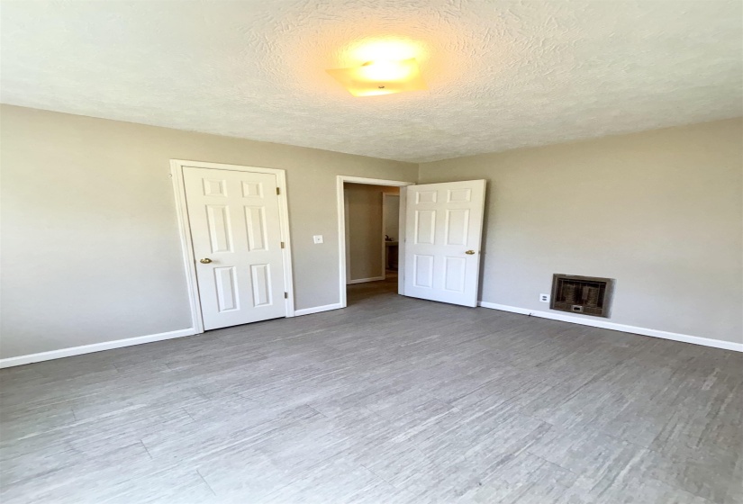 Unfurnished bedroom with heating unit, a textured ceiling, light wood-type flooring, and a closet