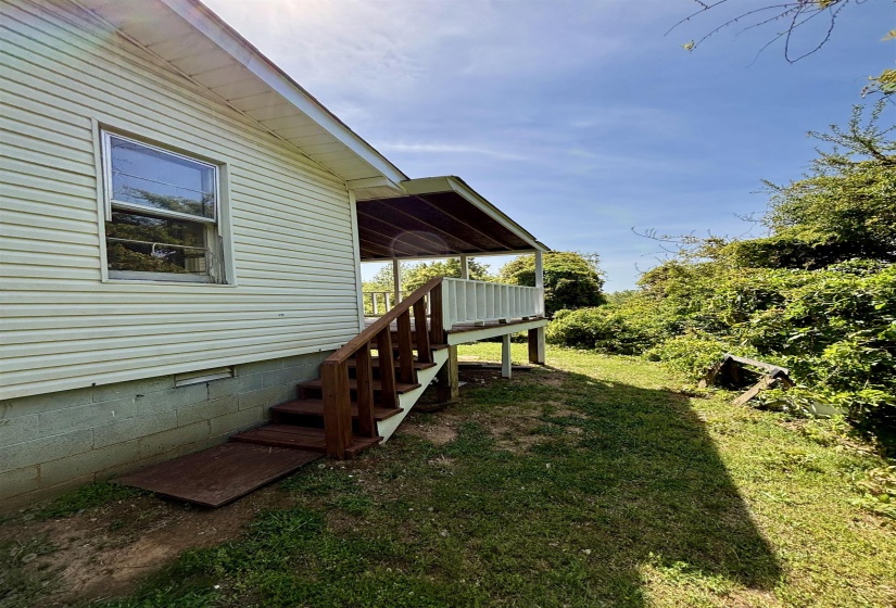 View of green lawn featuring a deck and stairs