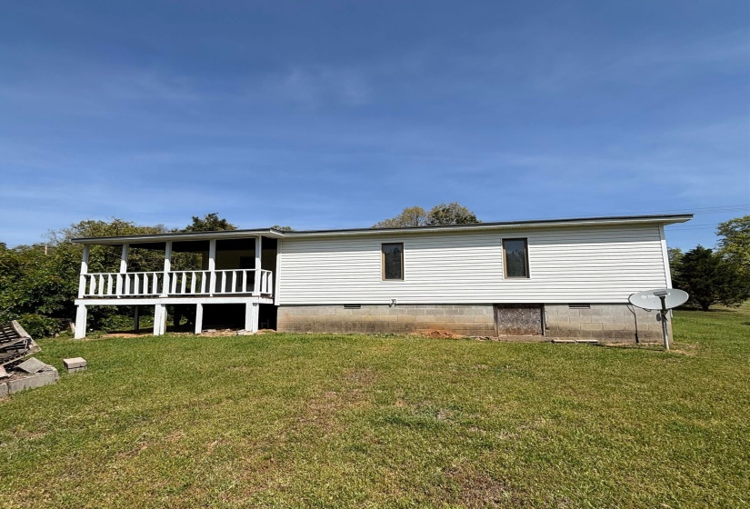 Back of property with crawl space and a lawn