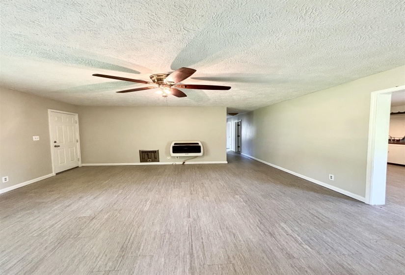 Unfurnished living room featuring light wood-style flooring, heating unit, a ceiling fan, and a textured ceiling