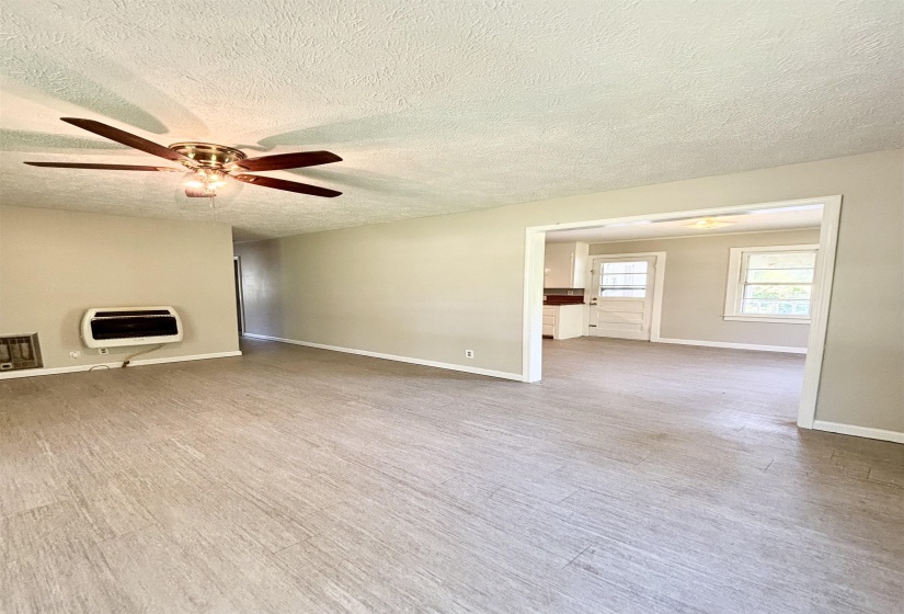 Unfurnished living room featuring a ceiling fan, heating unit, a textured ceiling, and light wood-type flooring