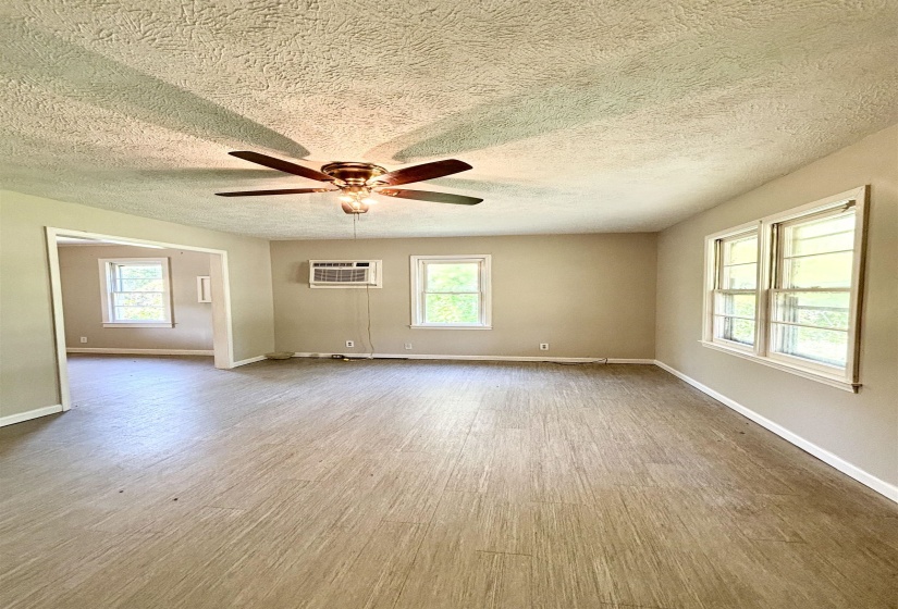 Unfurnished room with wood finished floors, healthy amount of natural light, ceiling fan, and a textured ceiling