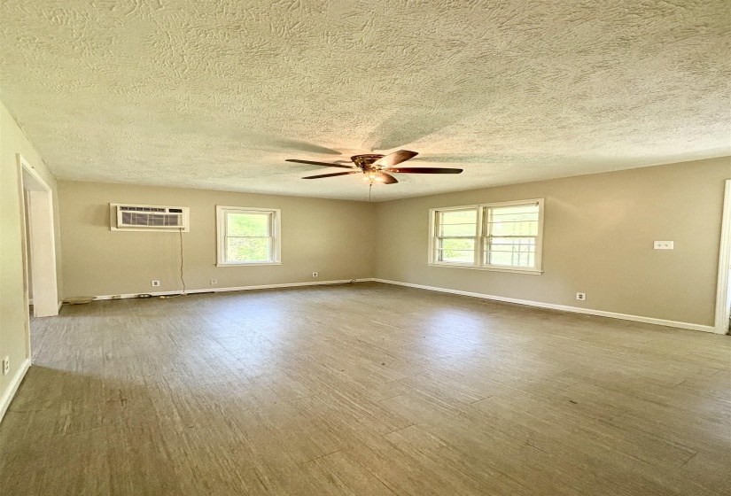 Spare room with wood finished floors, plenty of natural light, ceiling fan, and a textured ceiling