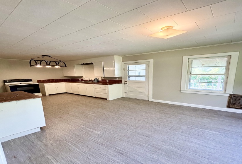 Kitchen with range with electric stovetop, dark countertops, white cabinets, crown molding, and light wood-type flooring