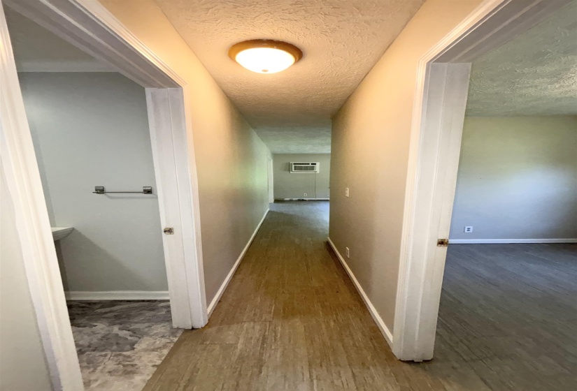 Hall with a textured ceiling and wood finished floors