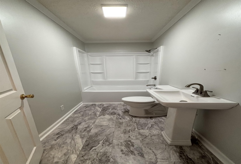 Full bathroom with a textured ceiling and washtub / shower combination
