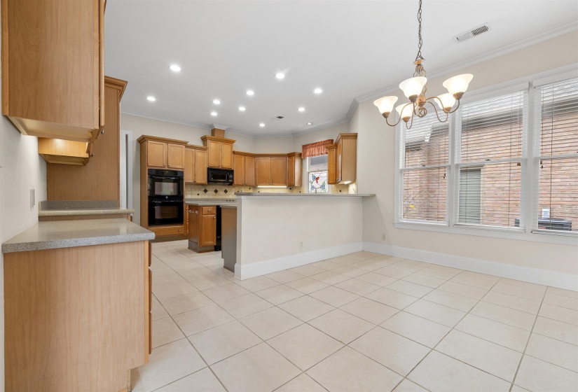 Kitchen with hanging lights, light tile patterned flooring, a peninsula, light countertops, and ornamental molding