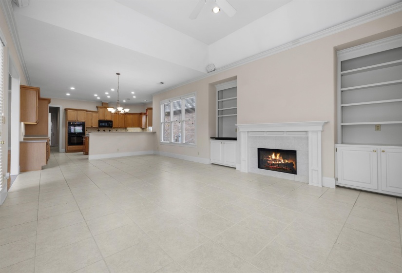 Unfurnished living room featuring built in shelves, ornamental molding, light tile patterned flooring, a fireplace, and suspended lighting