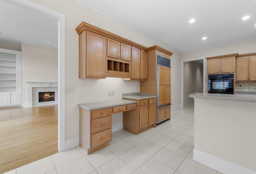 Kitchen with built in study area, recessed lighting, black oven, a lit fireplace, and built in shelves