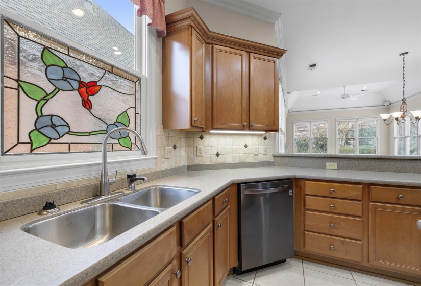 Kitchen featuring wood finish cabinets, stainless steel dishwasher, tasteful backsplash, crown molding, and lofted ceiling