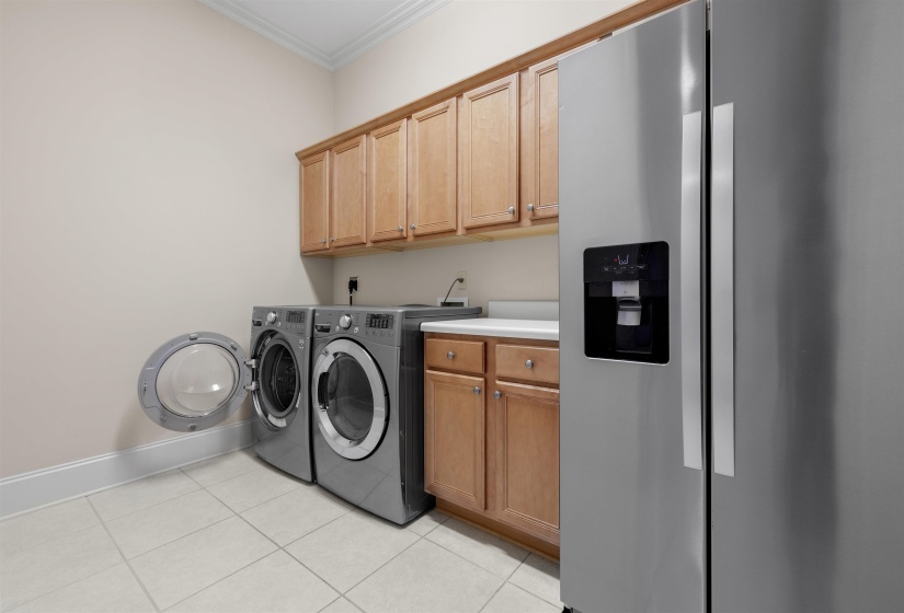 Laundry room with crown molding, light tile patterned floors, and washer and clothes dryer