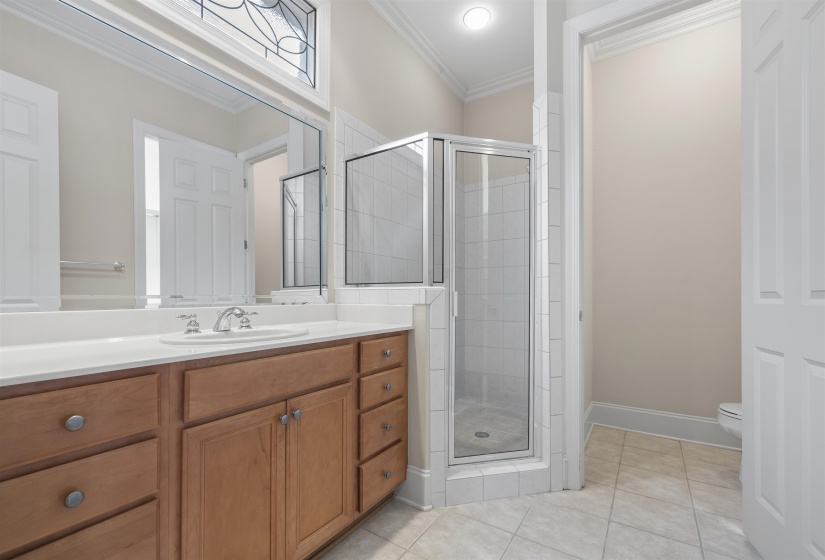 Bathroom featuring ornamental molding, a shower stall, vanity, and light tile patterned flooring