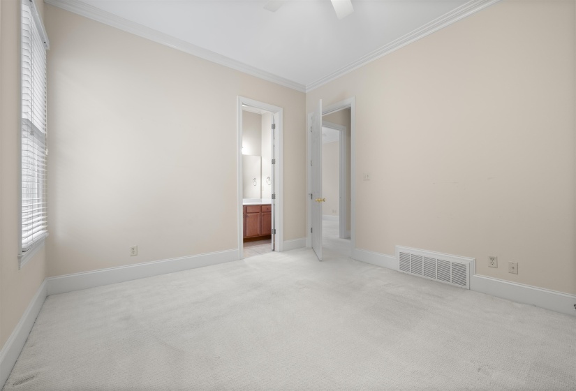 Unfurnished bedroom with ornamental molding, carpet floors, ensuite bath, and ceiling fan