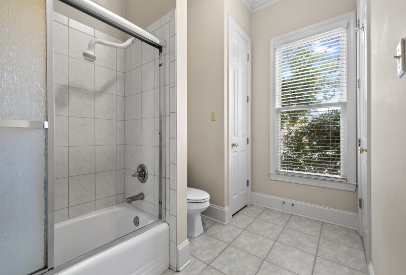 Full bathroom featuring enclosed tub / shower combo, light tile patterned floors, and ornamental molding