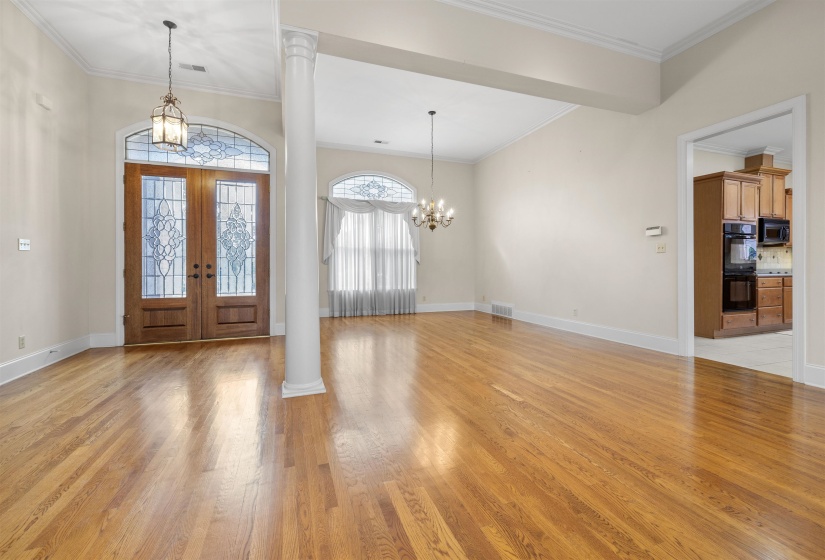 Foyer with suspended lighting, ornamental molding, light wood-style floors, and french doors