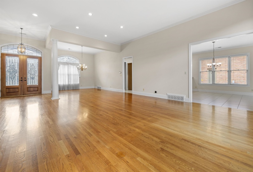 Unfurnished living room featuring a chandelier, french doors, crown molding, and light wood-style flooring
