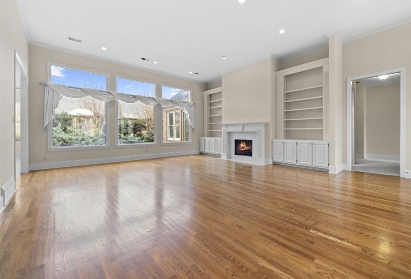 Unfurnished living room with built in shelves, light wood-type flooring, a premium fireplace, recessed lighting, and crown molding