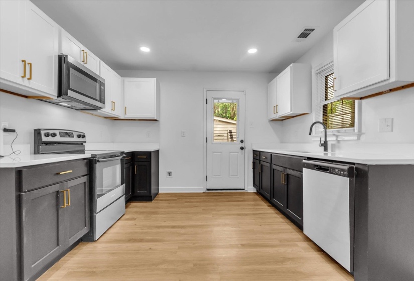 Dual tone kitchen featuring two tone cabinets, stainless steel appliances, light wood-type flooring, recessed lighting, and light stone countertops