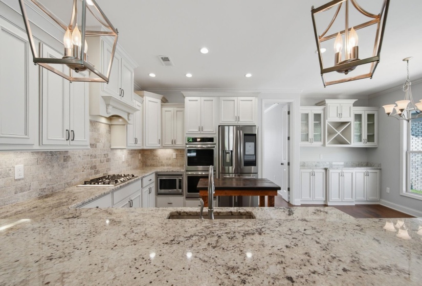 Kitchen featuring a chandelier, white cabinetry, light stone counters, tasteful backsplash, and stainless steel appliances