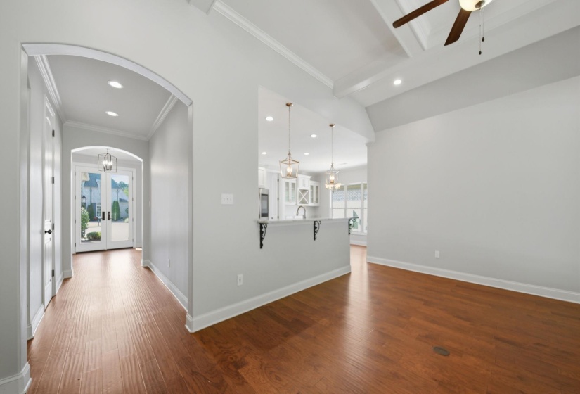 Corridor featuring dark wood finished floors, a chandelier, arched walkways, and crown molding