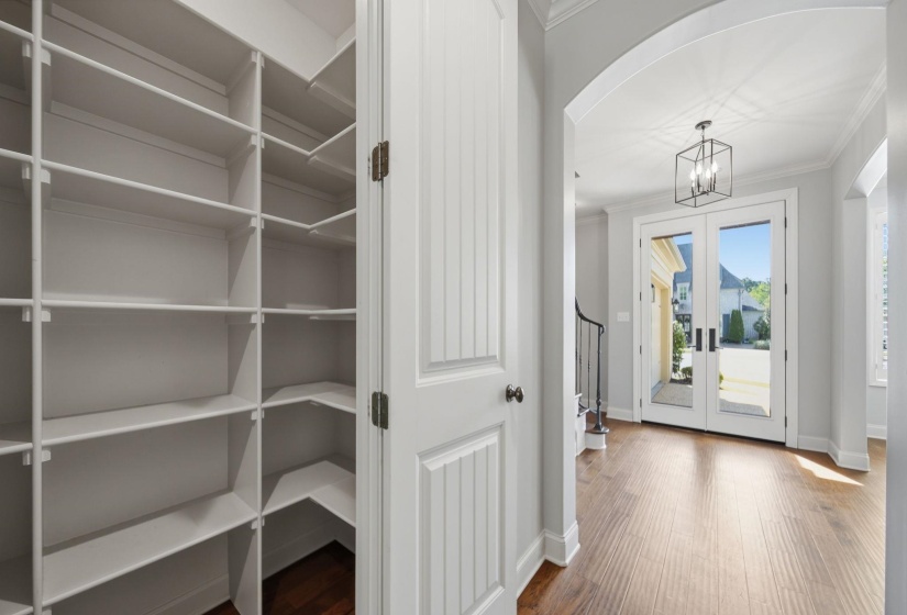 Foyer entrance featuring arched walkways, french doors, dark wood-type flooring, crown molding, and a chandelier