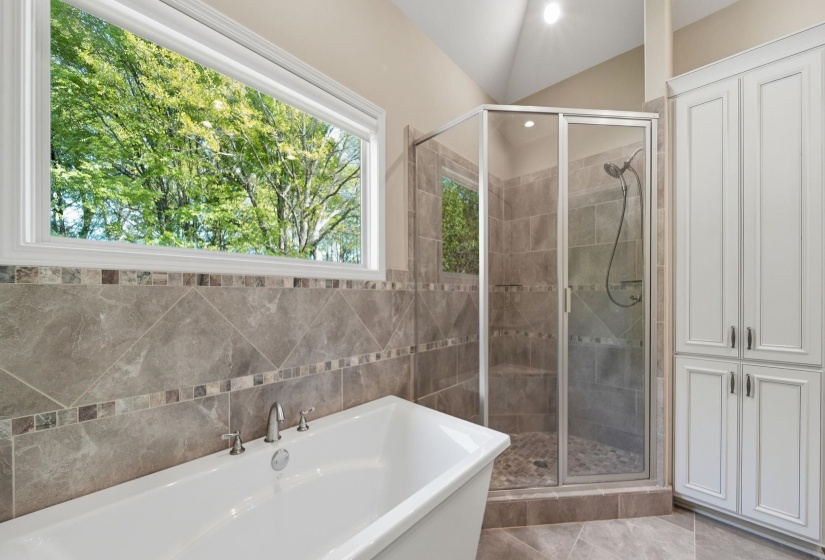 Full bath featuring a freestanding tub, a shower stall, and tile walls