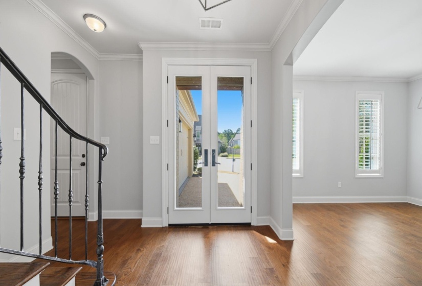 Foyer entrance featuring french doors, dark wood finished floors, arched walkways, and ornamental molding