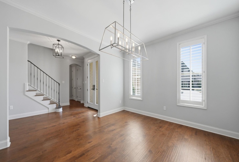 Unfurnished dining area featuring crown molding, arched walkways, a chandelier, and dark wood-style floors