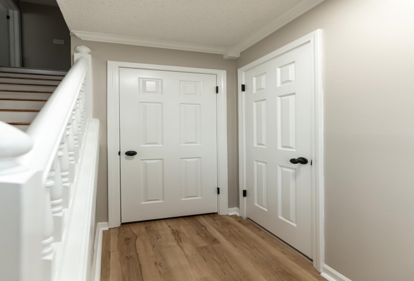 Doorway with wood finished floors, crown molding, and a textured ceiling