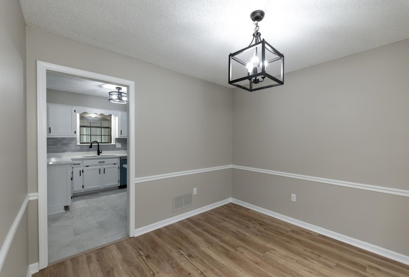 Unfurnished dining area featuring a textured ceiling, light wood-style floors, and a chandelier