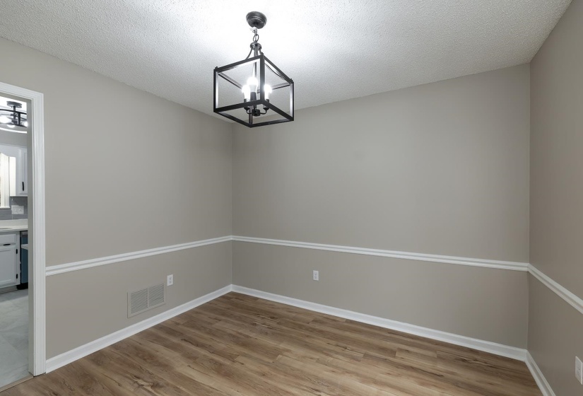 Unfurnished dining area featuring a textured ceiling, a chandelier, and light wood-type flooring