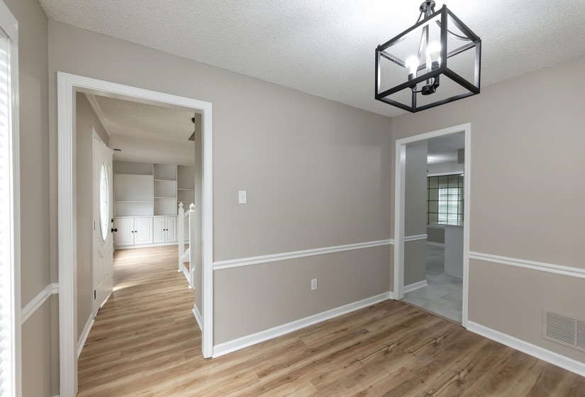 Unfurnished dining area with light wood-type flooring, a textured ceiling, and suspended lighting