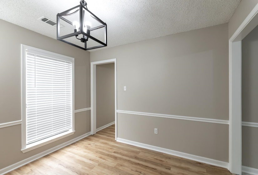 Unfurnished dining area featuring light wood-style floors, a textured ceiling, and a chandelier