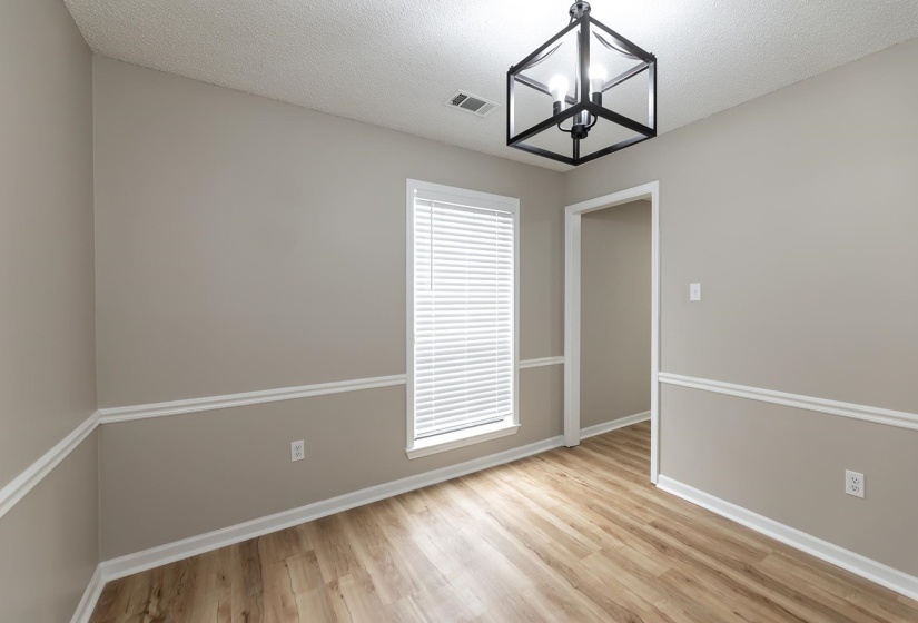 Unfurnished dining area with light wood-style floors, a textured ceiling, and a chandelier