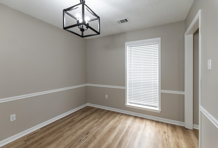 Empty room with light wood-style flooring, a chandelier, and a textured ceiling