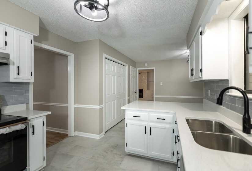 Kitchen featuring backsplash, electric stove, white cabinetry, a textured ceiling, and light stone counters