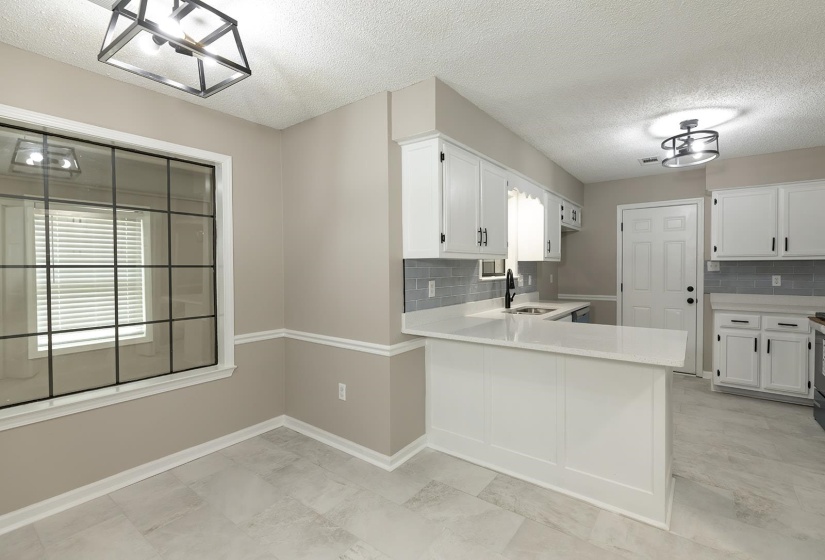 Kitchen with tasteful backsplash, white cabinetry, a textured ceiling, and a peninsula