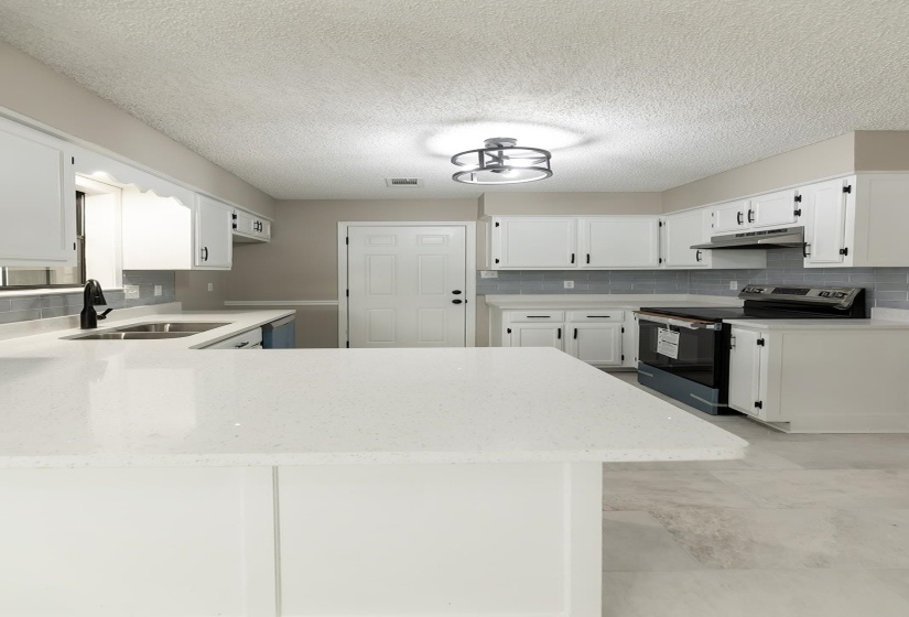 Kitchen with white cabinets, decorative backsplash, stainless steel appliances, a peninsula, and a textured ceiling