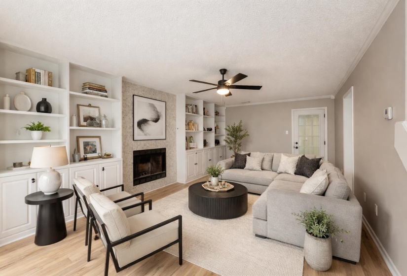 Living area featuring a textured ceiling, a fireplace, crown molding, a ceiling fan, and light wood finished floors