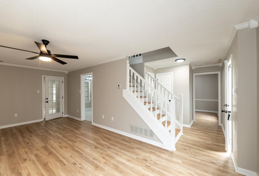 Entrance foyer featuring ornamental molding, light wood-style flooring, a ceiling fan, and a textured ceiling